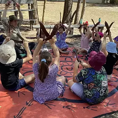 areta leading the children in a musical activity with seedpods